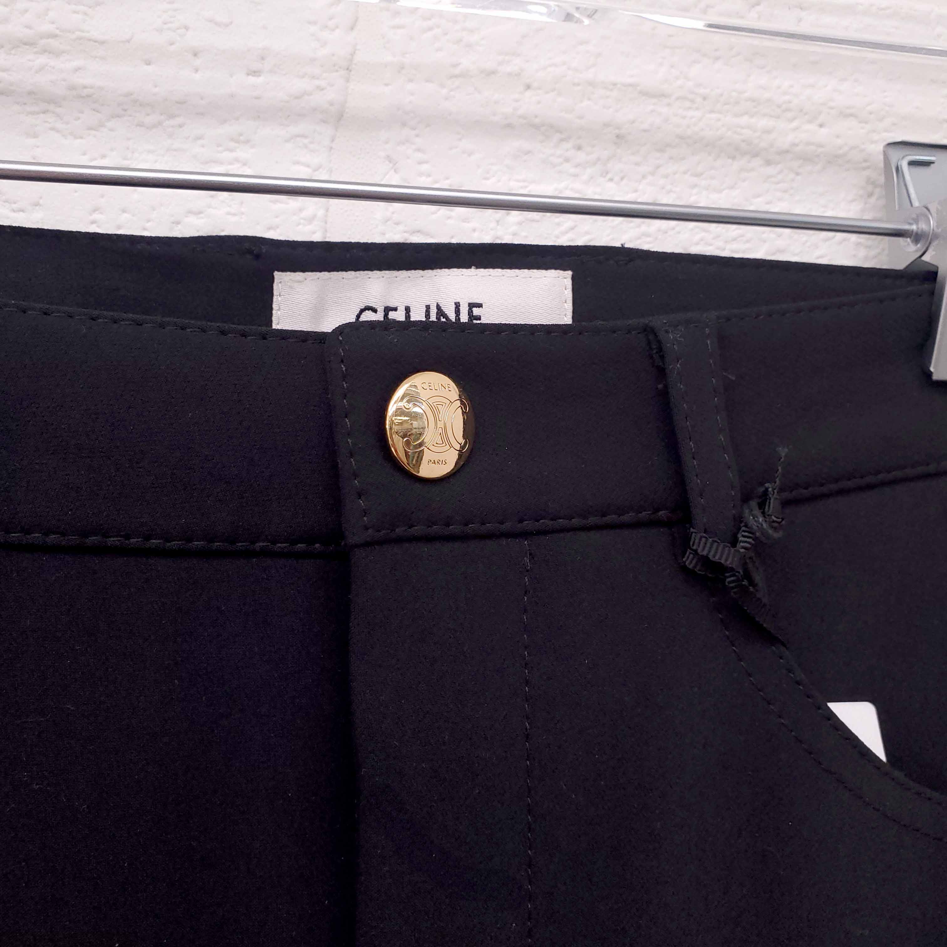 Black pants with a gold button and visible Celine label on a white background