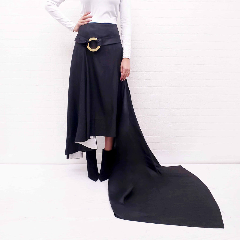 Person wearing a long Celine Runway black skirt with a gold belt on a white background