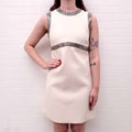 White Celine runway dress with silver embellishments worn by a person against a white brick wall.